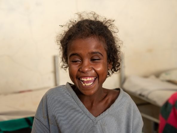 Etwa neujähriges, lachendes Mädchen.