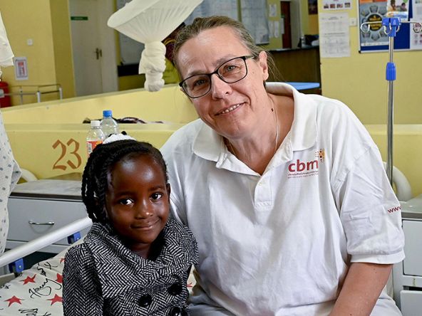 Eine Ärztin sitzt mit einem Mädchen auf einem Krankenbett.