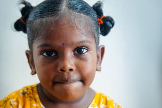 Ein etwa fünfjähriges Mädchen mit kleinen dunklen Zöpfchen. 