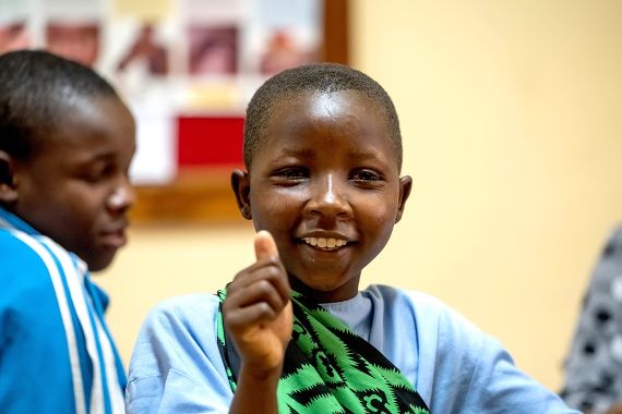 Ein etwa zehnjähriges Mädchen hält den Daumen hoch und lacht.