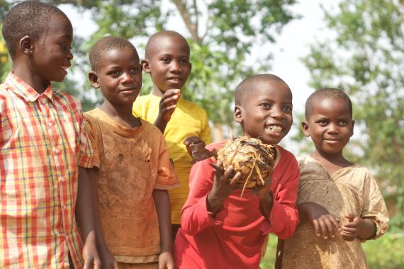Sechs Jungen zwischen etwa zehn und zwölf Jahren stehen nebeneinander. Einer hält einen frunden Klumpen in der Hand, der von einer Schnur zusammengehalten wird.