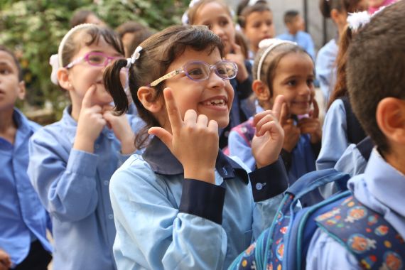 Kinder in blauer Schuluniform, die mit den Händen Zeichen der Gebärdensprache machen.
