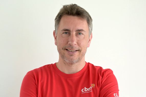 Porträt eines Mannes im roten T-Shirt mit CBM-Logo