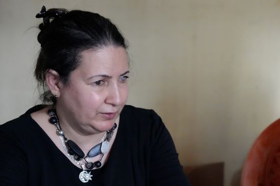 Porträt einer Frau mit dunklem, hochgestecktem Haar und einer Halskette mit schwarzen und silbernen Kugeln. Sie trägt ein schwarzes Shirt.