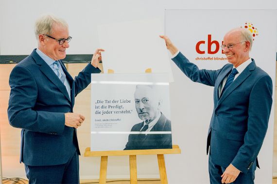 Zwei Männer stehen neben einem Schild. 