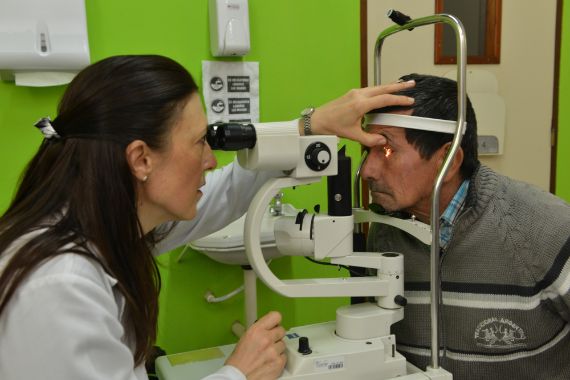 Graue-Star-Operation in Deuschland: Eine Frau untersucht mit einer Spaltlampe die Augen eines Mannes.