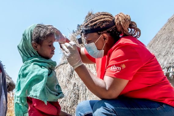 Eine Frau untersucht die Augen eines kleinen Mädchens.