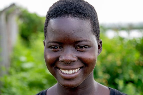 Lachendes afrikanisches Teenager-Mädchen mit einer weißen Pupille