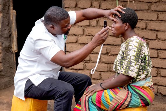 Ein afrikanischer Mann testet mit dem Handy die Sehkraft einer afrikanischen Frau.