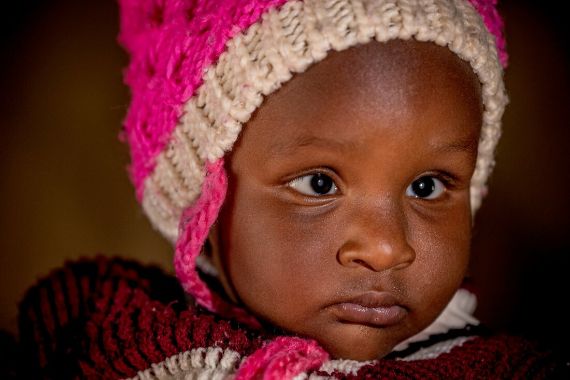 Ein kleiner Junge mit Wollmütze und weißen Flecken in den Augen. 