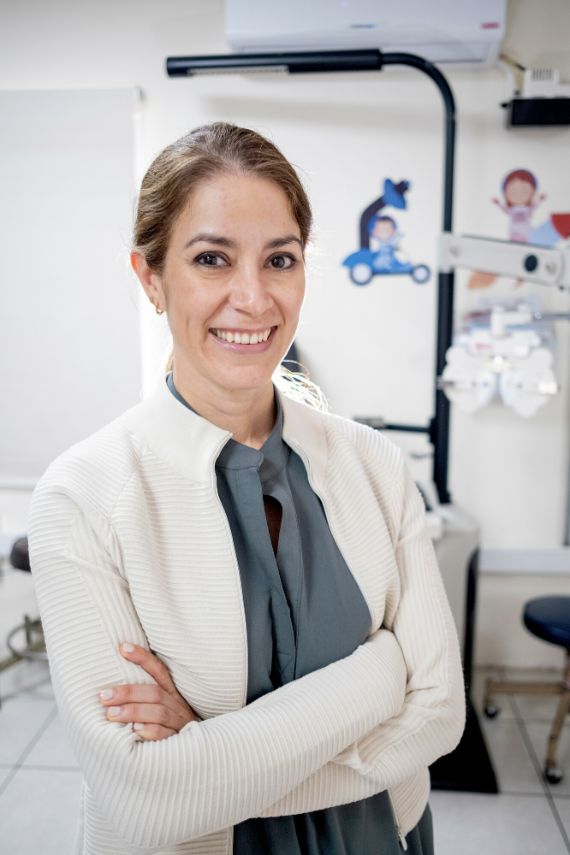 Ein Frau in einem Arztkittel blickt lächelnd in die Kamera.